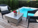Edelstahl Feuerschale als Tisch auf Holzterrasse, gedeckt mit Wein und Blumen, am Pool
