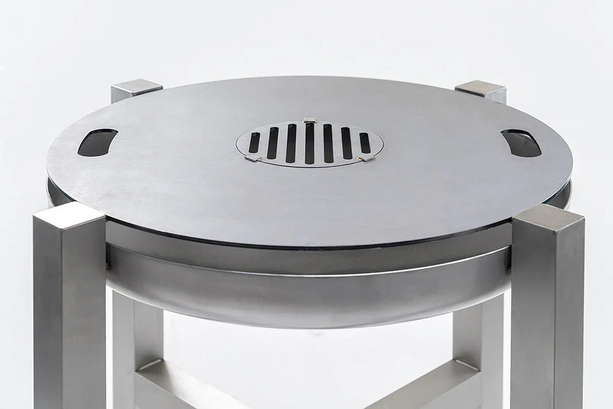 Edelstahlgrill und Feuerschale mit runder Grillplatte und modernem Design auf hellem Hintergrund