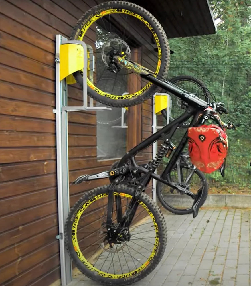 MTB Fahrrad an vertikaler Wandhalterung mit gelbem Fahrradlift im Außenbereich