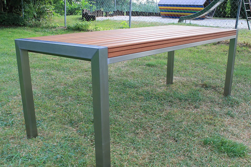 Moderner Gartentisch aus Edelstahl und Holz auf Rasen im Außenbereich