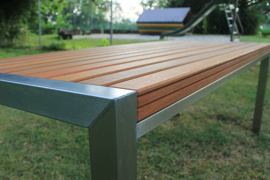 Moderner Gartentisch aus Edelstahl und Holz auf Rasen im Freien