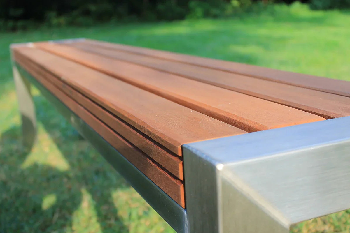 Moderne Gartenbank mit Edelstahl-Gestell und Holz-Sitzfläche im Garten