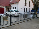 Modernes Hoftor aus Metall mit Briefkasten vor Einfamilienhaus, gepflasterte Einfahrt