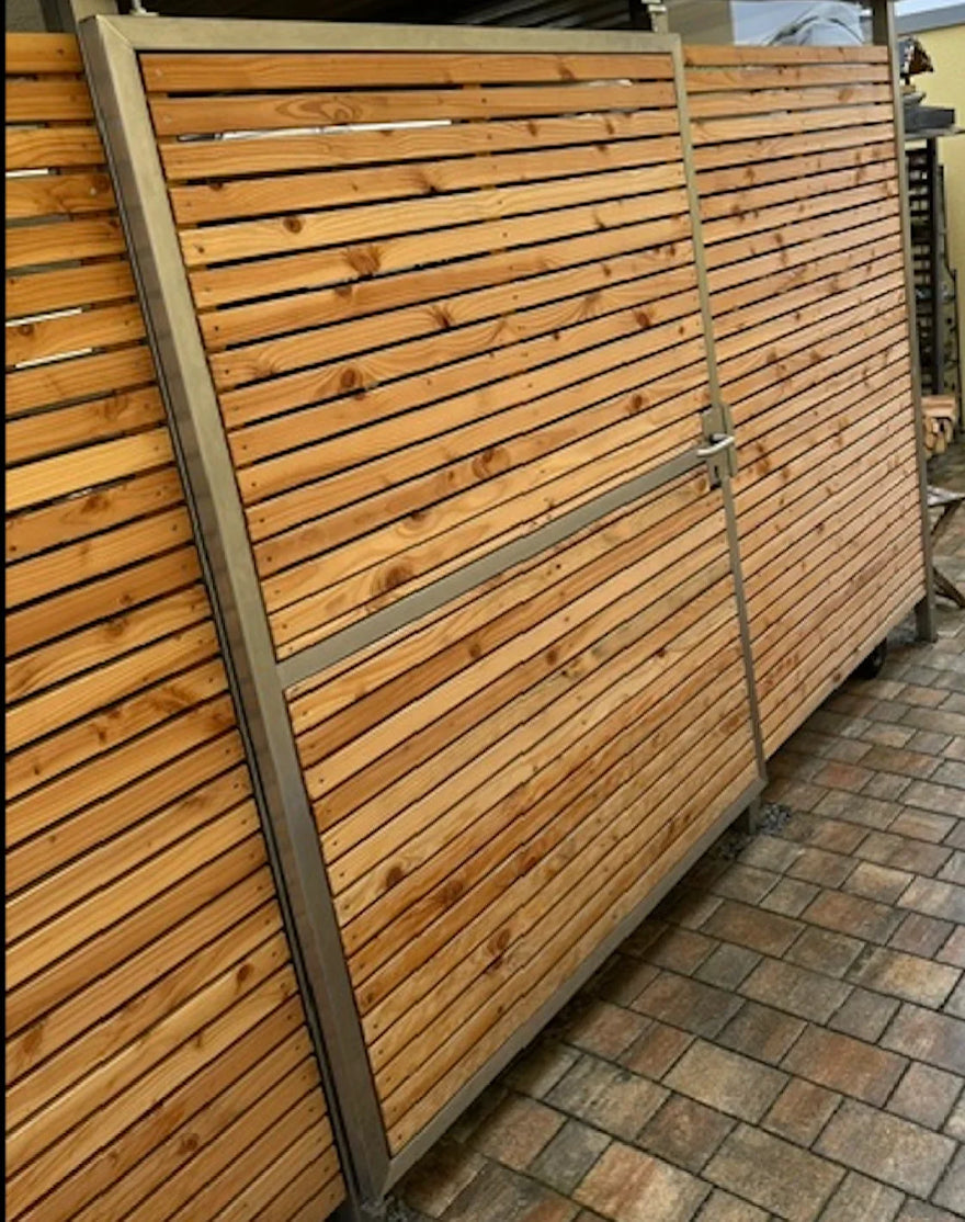Holztür für Fahrradhaus mit stabilem Metallrahmen auf gepflastertem Boden