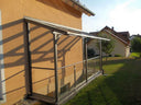 Kellerabgangsüberdachung aus Metall und Glas an einem Wohnhaus im Garten