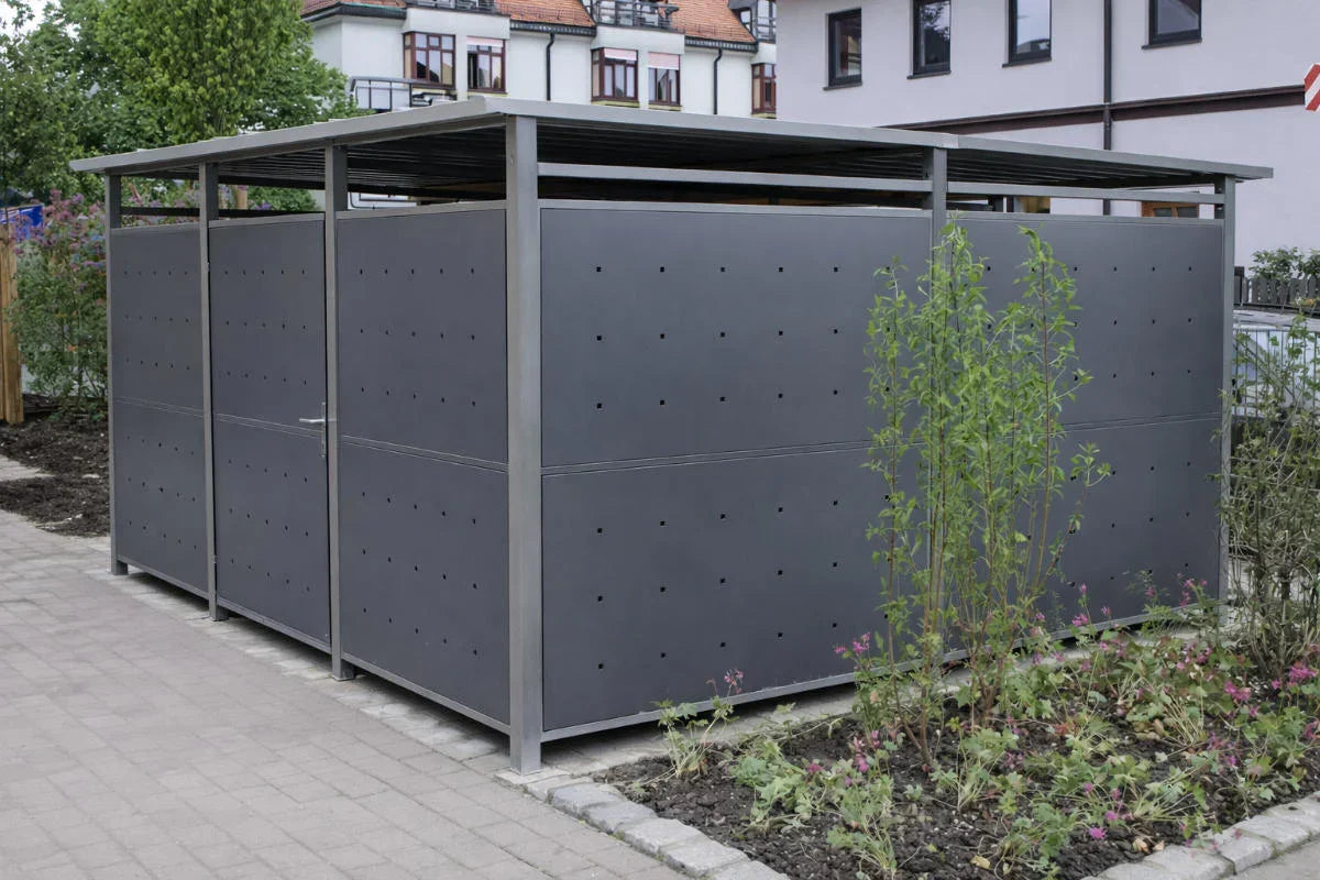 Modernes Mülltonnenhaus aus Metall in Anthrazit, aufgestellt im Außenbereich neben einem Weg.