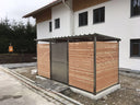 Mülltonnenhaus aus Holz und Metall mit Flachdach vor modernem Wohnhaus