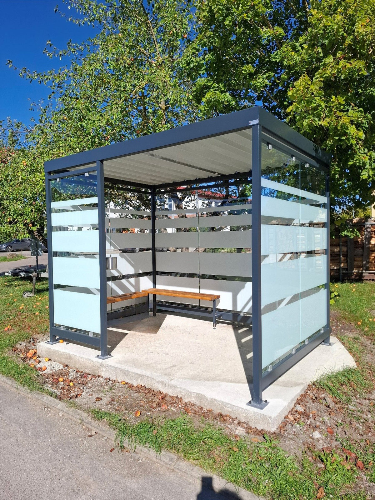 Überdachte Wartehalle aus Stahl in RAL 7016 Anthrazitgrau mit ESG-Siebdruckglas und Sitzbank über Eck