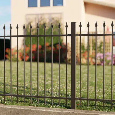 Schmuckzaun aus Metall mit Zierspitzen vor Garten und Haus bei Tageslicht