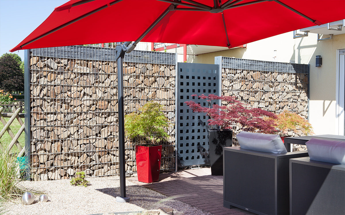 Steinzaun SAPHIR als Sichtschutz an einer Terrasse mit Sonnenschirm